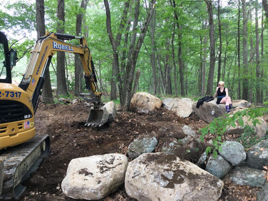 During construction, Cecily Wardell, director of strategic initiatives and mother of two Birches students, posed among the giant boulders as they were moved into a rough circle.